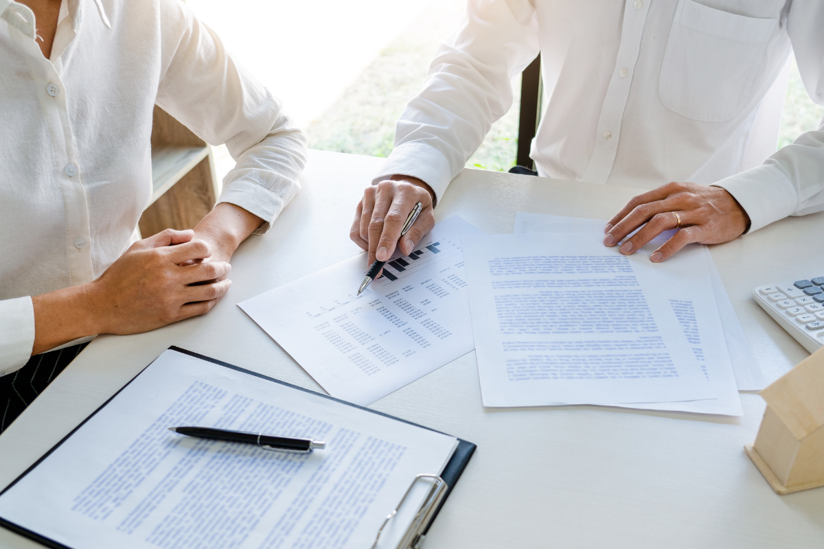 Two professionals reviewing real estate exchange documents and financial reports at a meeting table representing a qualified intermediary consultation